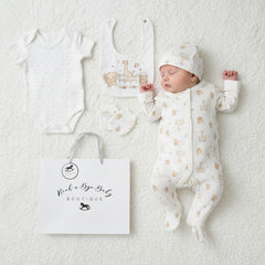 A sleeping baby wearing a white cotton unisex play time 5 piece layette set with beige animal prints and matching hat and bib