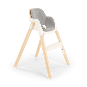 Modern Nuna BRYN highchair with a wooden frame, gray upholstered seat, and white plastic base for versatile use
