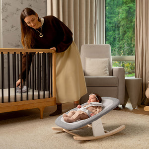 Gray and white baby rocker with wooden rocking base in the nuna bryn highchair and newborn rocker bundle heritage