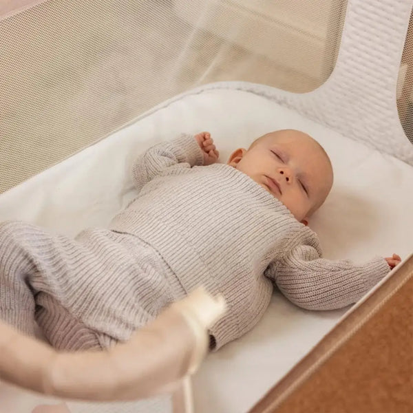 OBaby Cloud Bedside Crib Bundle Including Fitted Sheets – Oatmeal with a sleeping baby in cozy outfit.